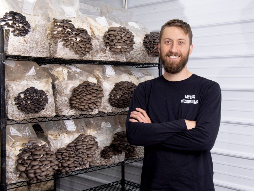 Eric Myers beside a shelf with cultivated mushrooms 2