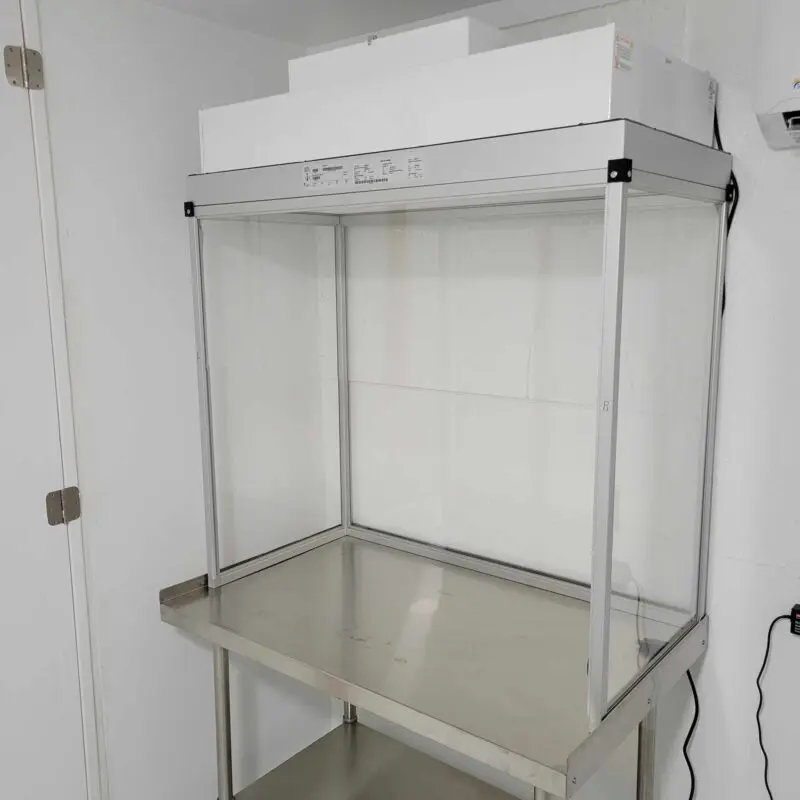 A stainless steel shelf with a Vertical Flow Cabinet 2x4 ft Flowhood Fan Filter Unit New 120V *Freight Not Included* in a small room.