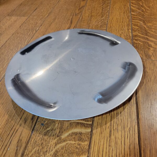 A silver plate sitting on a wooden floor.