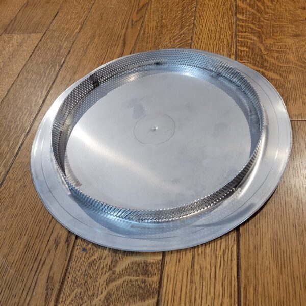 A round metal plate on a wooden floor.