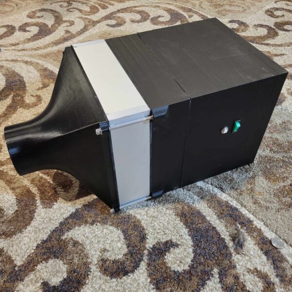 A 10"x10" HEPA Module 120v made of cardboard with a silver tape accent resting on a patterned carpet.