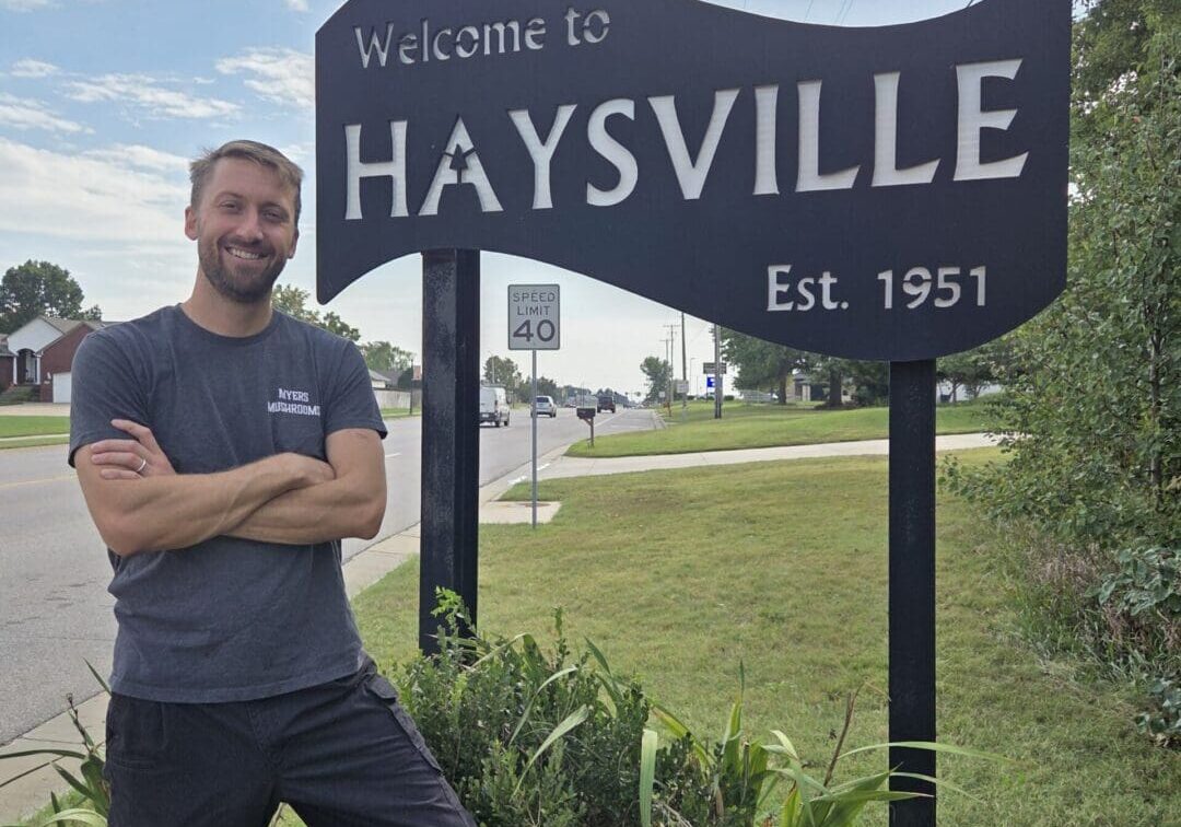 Man standing by Haysville welcome sign.